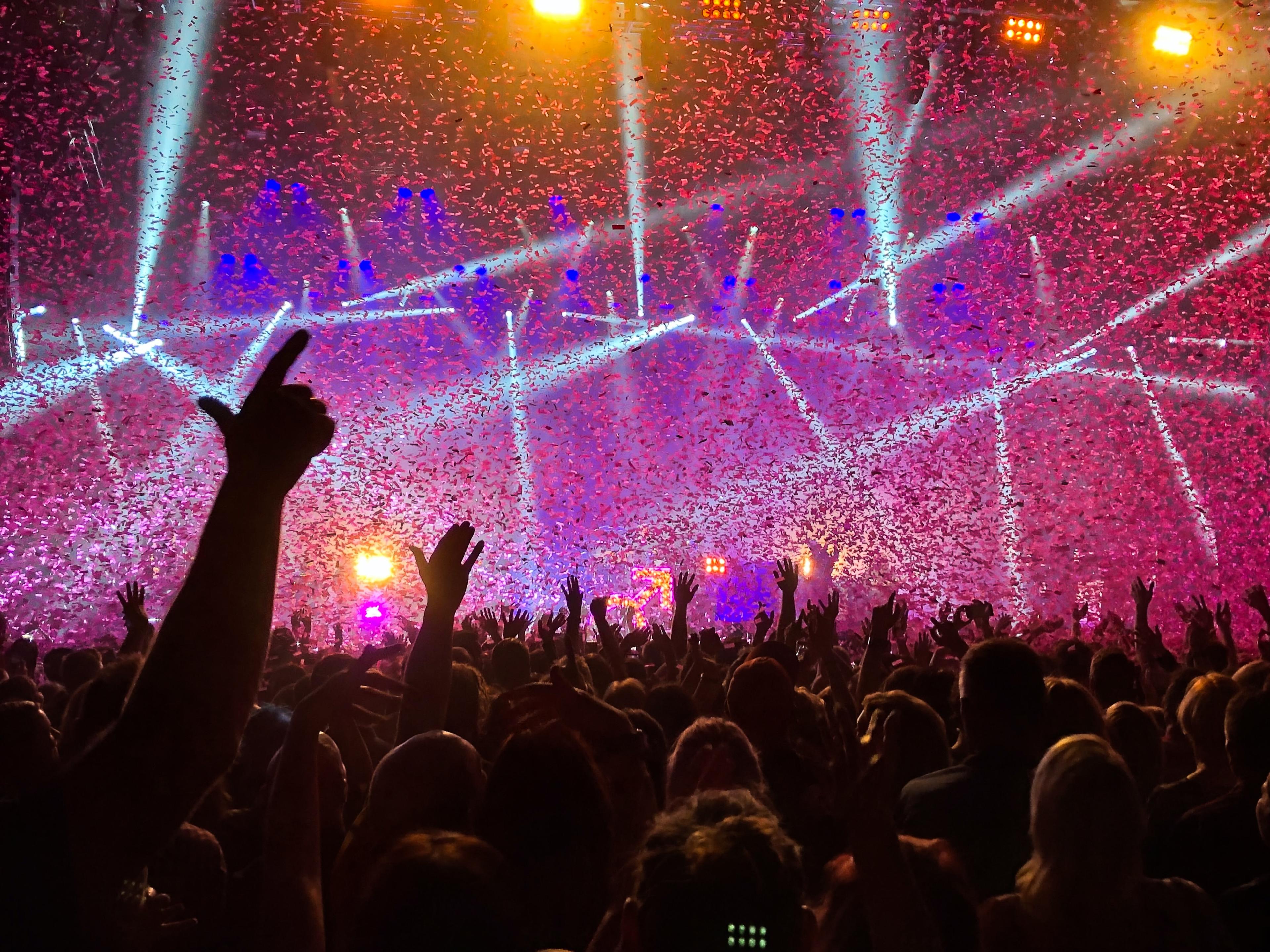 A picture showing a dancing crowd with a lot of confetti and laser effects.