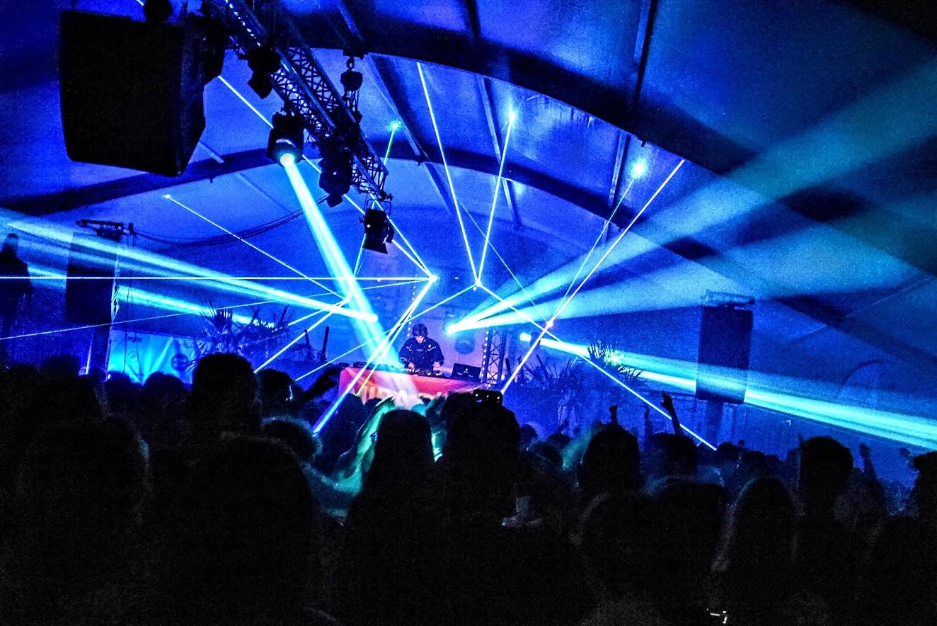Een foto van DJ LOST voor een publiek met blauwe laserstralen in de foto.