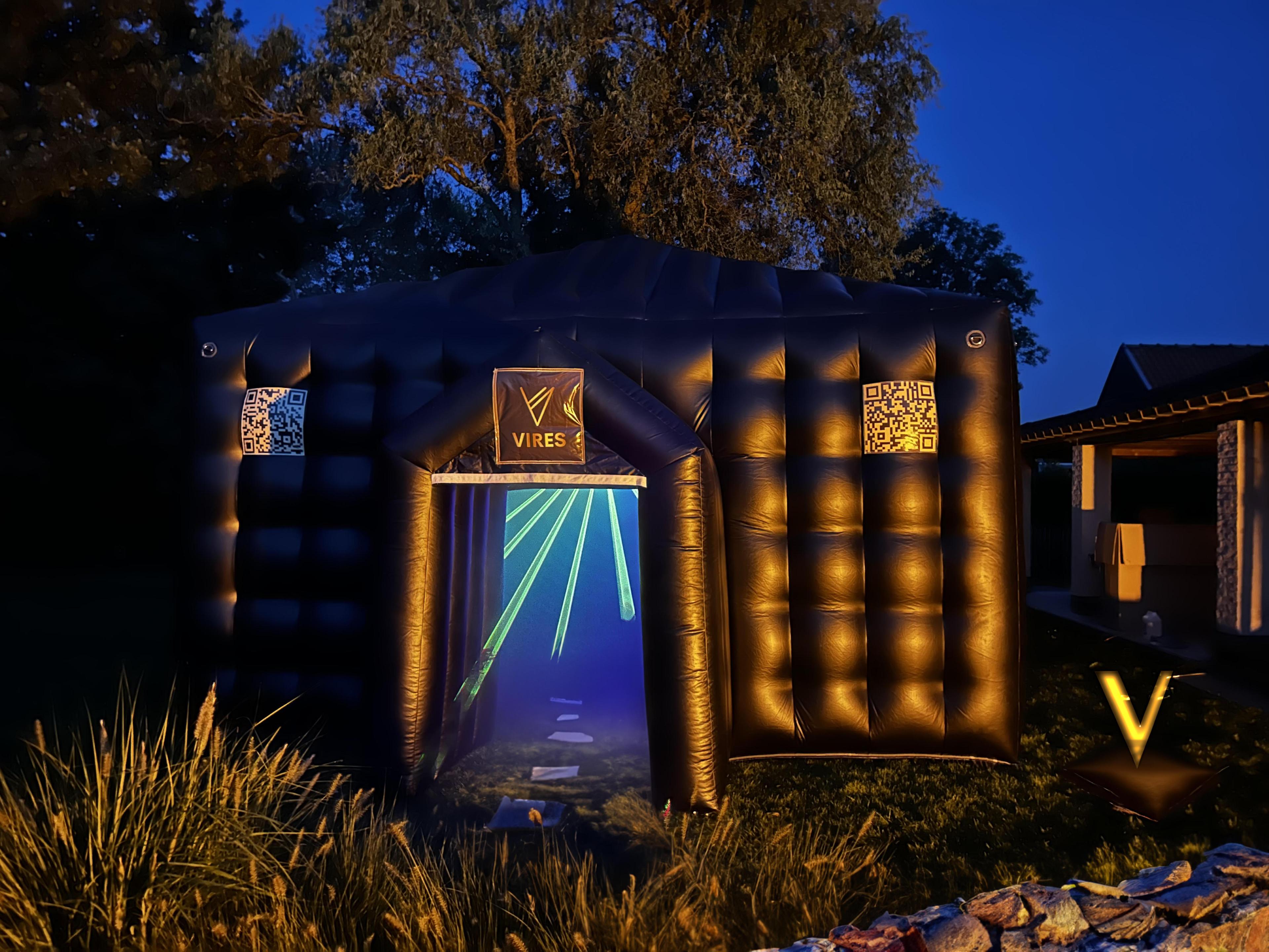 Photo of the entrance of an inflatable black party tent with laser beams emanating from the tent.